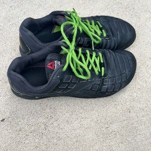 Black Reebok sneaker with green laces